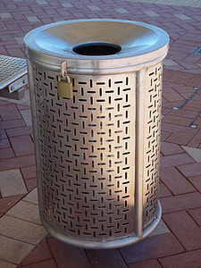 round gray metal trash bin on brown paver block thumbnail