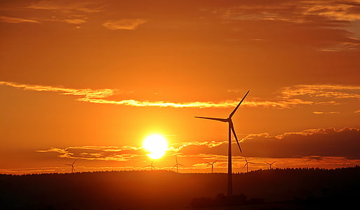 windmills under orange sky during golden hour thumbnail