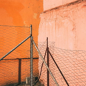 gray cyclone fence near wall during daytime thumbnail