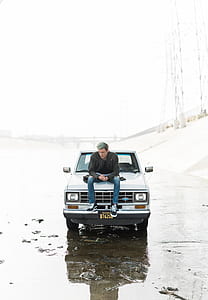 man sitting on white Ford pickup truck thumbnail