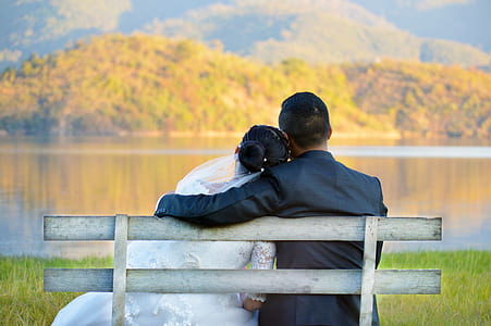 man and woman sitting on white wooden bench thumbnail