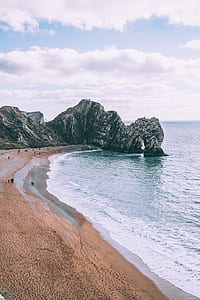 people on seashore near gray rock formation thumbnail