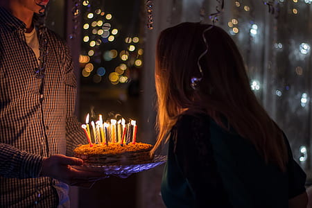 man holding cake with candle in front of woman thumbnail