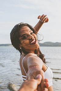 woman wearing white bikini top holding hand during daytime thumbnail