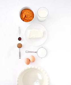 flat lay photography of butter served in white plate beside glass cup, measuring cup, bowl, and eggs thumbnail