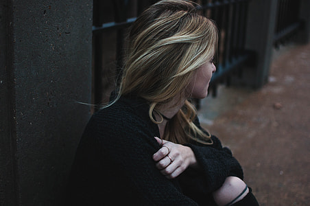 woman wearing jacket sitting beside fence during day thumbnail