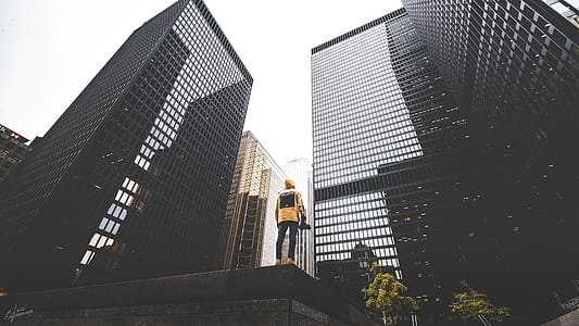 low angle photography of person standing near curtain wall buildings thumbnail