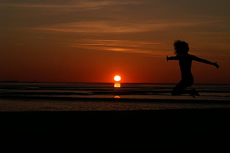 woman taking jump shot at beach during dusk thumbnail