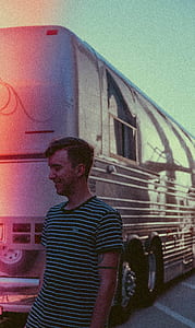 man smiling beside white bus thumbnail