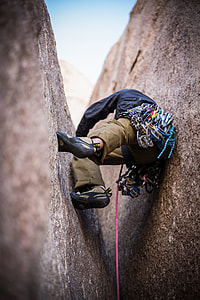 man doing rock climbing in between of gray rock formation thumbnail