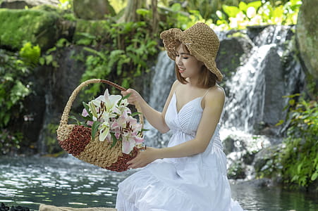Woman Holding Basket While Sitting Near Waterfall thumbnail