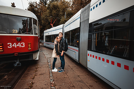 couple standing between trains during daytime thumbnail