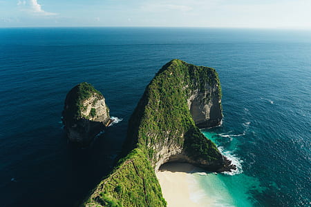 landscape photography of green rock formation in midst of body of water thumbnail