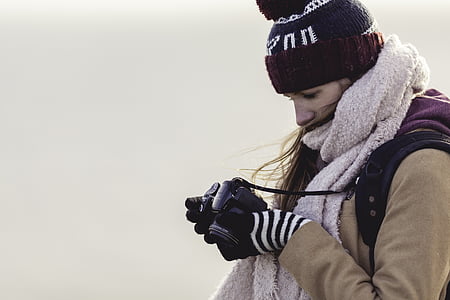 woman looking at the black DSLR camera thumbnail