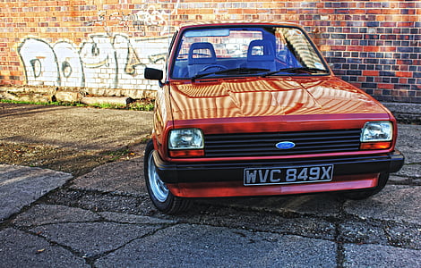 red Ford car parked near red bricked wall thumbnail