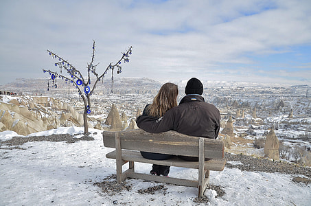 photo of couple sitting on brown bench while staring at the horizon thumbnail