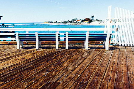 person taking photo of white metal hand rail near body of water at daytime thumbnail