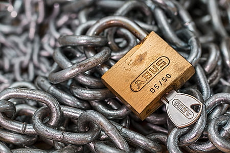brass Abus padlock with key on top of chains thumbnail
