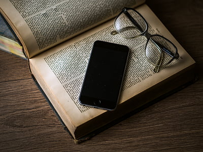 flat lay photography of space gray iPhone 6 on top of hardbound book beside black framed eyeglasses thumbnail