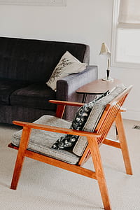 orange wooden armchair placed near brown sofa inside white painted room thumbnail