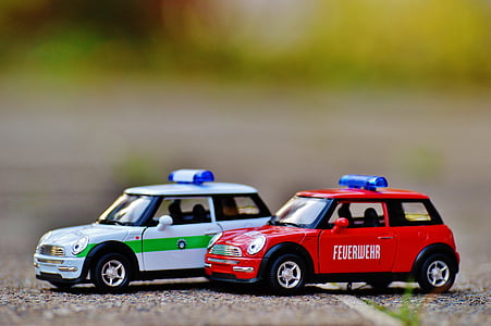 shallow depth of field photo of two red and white Mini Cooper scale models thumbnail
