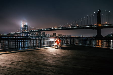 photography man in orange top under full-suspension bridge thumbnail
