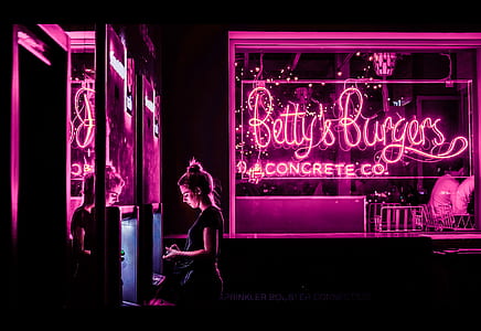woman standing beside Betty's Burger neon signage thumbnail