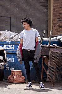 man standing beside a blue trash container thumbnail