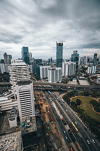 Aerial Photography of Building and Vehicle Passing on Road Under Gloomy Sky thumbnail