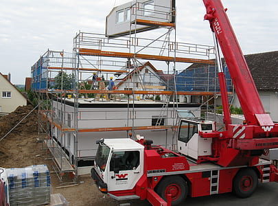 red and white crane truck lifting white building frame thumbnail