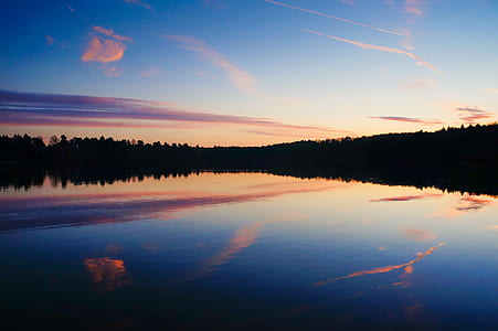 green trees reflecting on body of water during golden hours thumbnail