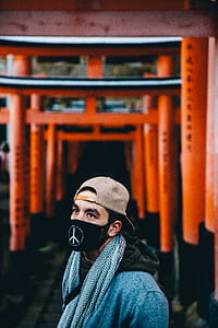 man wearing black mask and brown fitted cap near orange scaffolding in selective focus photography thumbnail