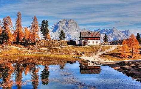 white and brown house near body of water at the foot of moutain thumbnail