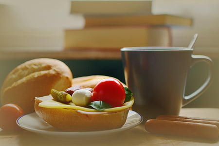 baked bread placed on white ceramic saucer near black ceramic mug placed on brown wooden table thumbnail