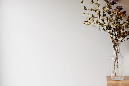 clear glass vase on brown wooden table inside room with white painted wall thumbnail