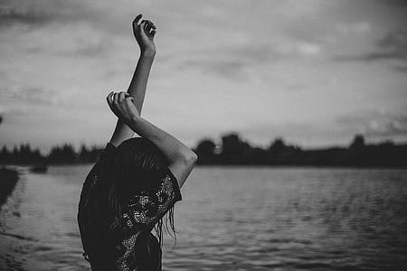 woman raising her hands near ocean during daytime thumbnail