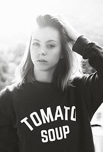 grayscale photo of woman wearing tomato soup-printed sweater holding hair thumbnail