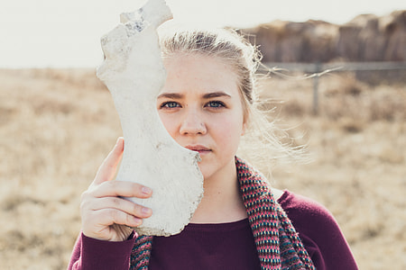 woman holding white stone fragment on grass field thumbnail