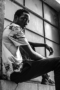 grayscale photo of man sitting beside the window thumbnail