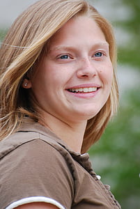close-up photo of woman wearing brown shirt smiling thumbnail