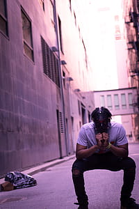 Man Crouching Near Building Wall Outdoor thumbnail
