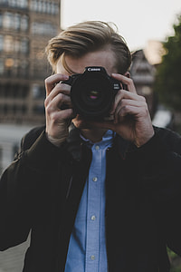 man holding Canon DSLR camera thumbnail