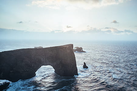 rock formations in body of water under cloudy sky during daytime thumbnail