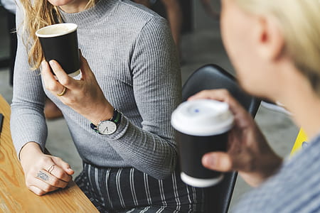 woman wearing gray long-sleeved shirt holding disposable drinking cup thumbnail