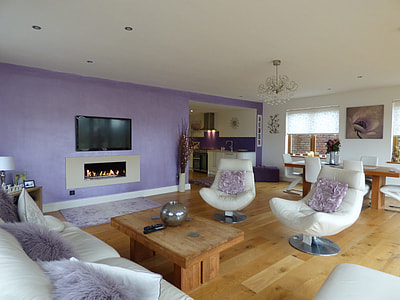 turned off TV on wall in front of white leather sofa set with purple fleece throw pillows thumbnail