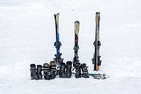 three snow skis, boots, and poles on snow thumbnail
