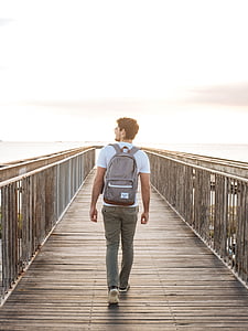 man in white shirt walking on beach dock thumbnail