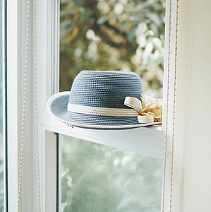 blue and white sun hat with flower accent placed on sash window thumbnail