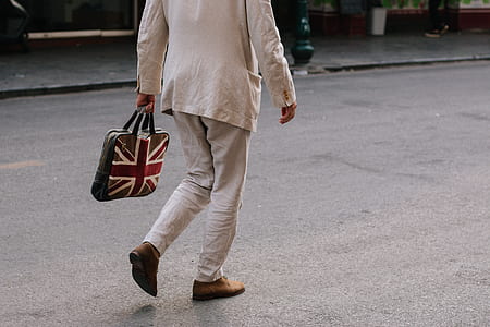 man walking while holding UK-themed bag on gray concrete road thumbnail