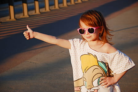 girl wearing white top doing thumbs up hand gesture thumbnail